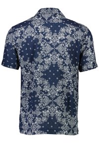 Camisa de manga corta hecha de tela azul marino con un patrón de paisley blanco, con cuello y dobladillo recto. Presenta un diseño intrincado en todo el tejido.
