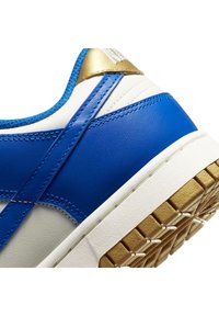 Blue leather sneaker with white and gold accents, featuring a textured upper, padded collar, and a patterned rubber sole.