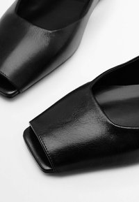Schwarze Sandalen mit offener Zehenpartie aus strukturiertem Leder, mit einer breiten, quadratischen Zehenpartie und einem glatten Innenraum. Minimalistisches Design mit einer eleganten Silhouette.
