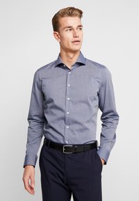 Koszula z długim rękawem w jasnoniebieskim kolorze, o g ładkiej fakturze i kołnierzyku typu spread. Białe guziki zdobią przód.