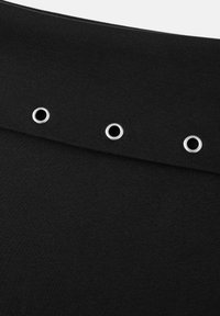 Tissu noir au toucher lisse avec trois œillets métalliques le long du bord, ajoutant un détail au design.