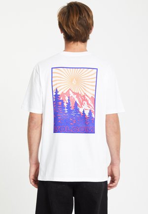 White cotton t-shirt featuring a colorful graphic of mountains, trees, and sun in pink and blue, with "VOLCOM" logo at the bottom.