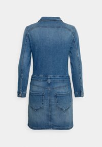 Vestido de ganga com mangas longas, gola e dois bolsos traseiros. Apresenta uma cor azul desbotada, design ajustado e detalhes de costura visíveis.