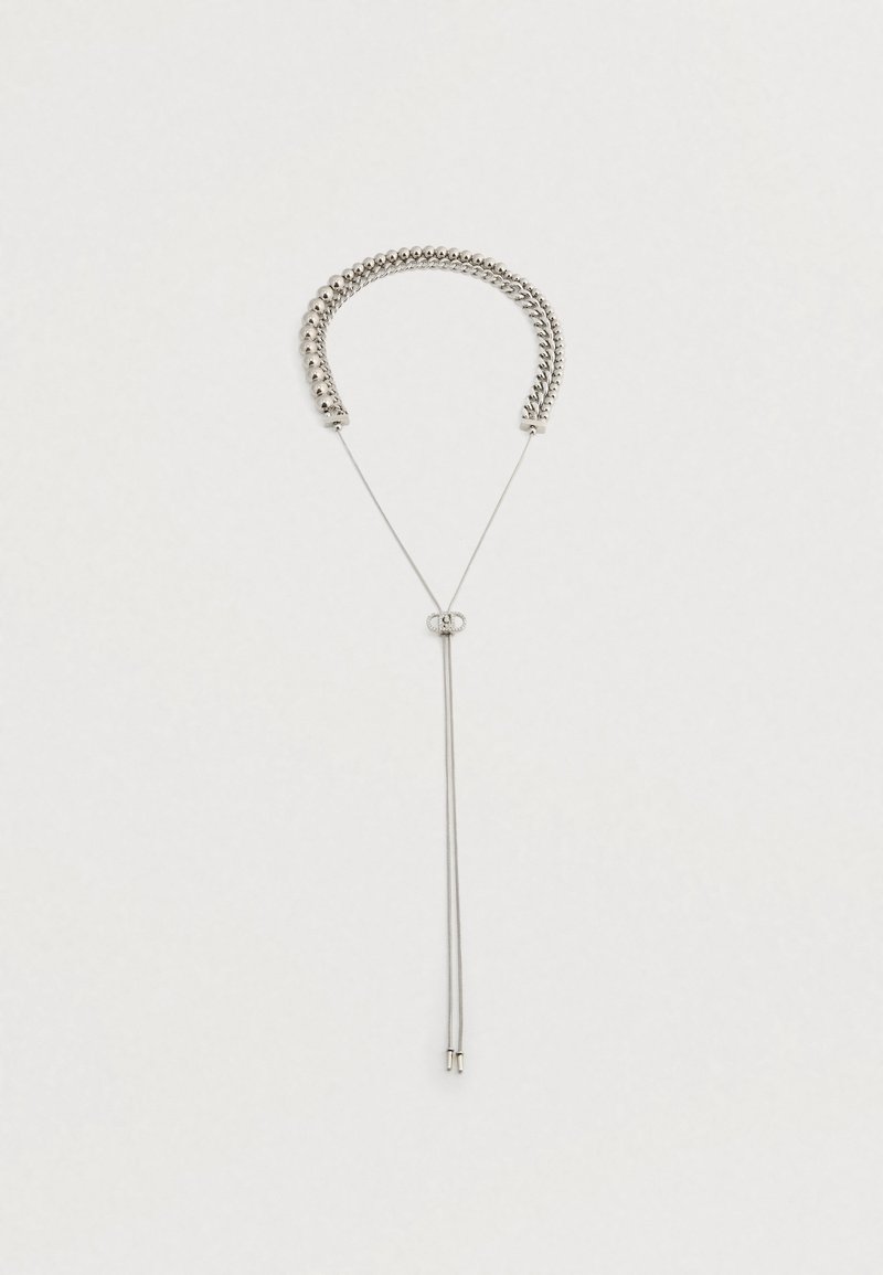 Sølvfarvet halskæde med to forskellige kædestilarter forbundet af en glidende lås med to hængende kædeender på en neutral baggrund.