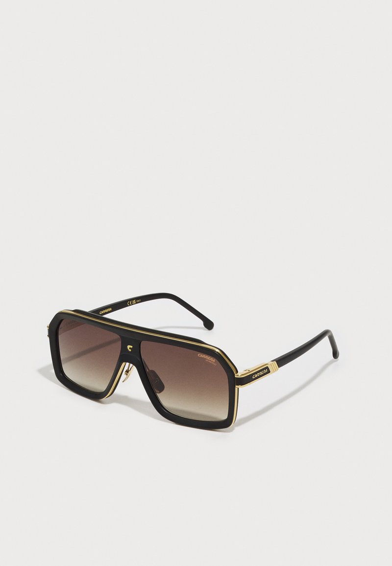 Gafas de sol de gran tamaño en negro y dorado con forma rectangular, lentes marrones degradados y un detalle prominente en el hardware lateral.