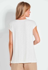 Weißes T-Shirt mit kurzen Ärmeln und lockerer Passform, mit rundem Ausschnitt und weichem Stoff. Von hinten gesehen, mit minimalen Details.