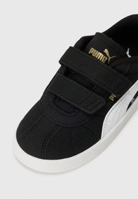 Basket noir Puma avec semelle blanche et bande latérale, dotée de deux sangles velcro et d'un logo Puma doré sur la languette et sur le côté.