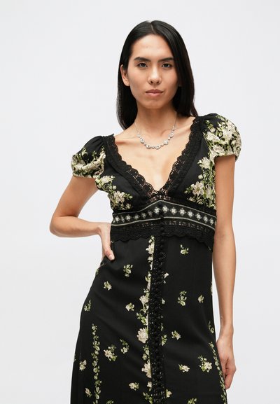 Zwarte bloemenjurk met ballonmouwen, kantafwerking, een diepe V-hals en knoopdetails aan de voorkant. Ontworpen met kleine witte en groene bloemen.