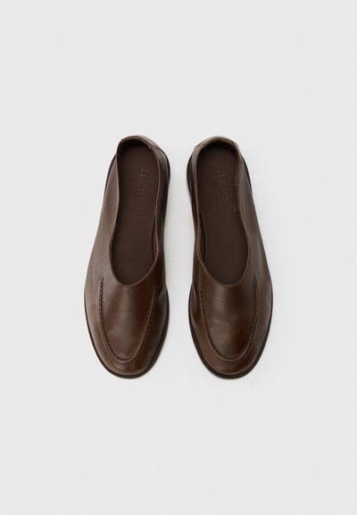 Chaussures marron en cuir à enfiler avec une finition lisse, un bout arrondi et un détail cousu le long de la tige, dotées d'une semelle basse et flexible.