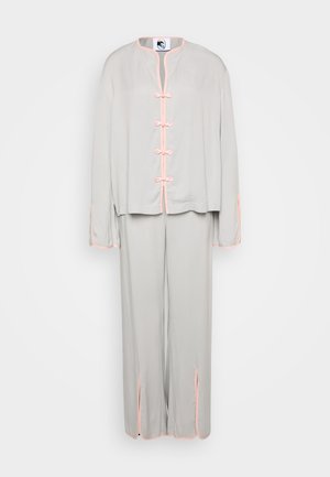 Ensemble deux pièces gris clair en tissu doux. Présente un col mandarin, des accents roses et des boutons en nœud sur la veste. Pantalon ample avec fentes.