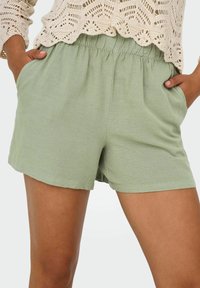 Lichtgroene shorts met een elastische tailleband, zijzakken en een zachte textuur. Eenvoudig ontwerp met een rechte snit en zonder zichtbare patronen.