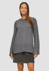 Pull en tricot gris avec un ourlet côtelé et des manches larges, assorti à une jupe sombre. Le tissu semble doux avec une coupe décontractée.