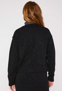 Maglione nero con lavorazione a maglia testurizzata, presenta macchie dorate, spalle cadenti e orlo a costine. Collo alto in grigio a contrasto.