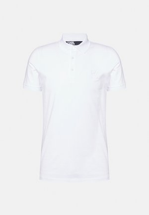 Λευκό πόλο μπλουζάκι από απαλό βαμβάκι, με κλασικό γιακά, τρεις κουμπάκια στη μέση και μικρό ανάγλυφο λογότυπο "K" στο στήθος.