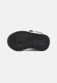 Černá gumová podrážka s texturovaným vzorem běhounu; obsahuje otisk kruhového loga. Čistý design, minimální zdobení, pevná konstrukce.