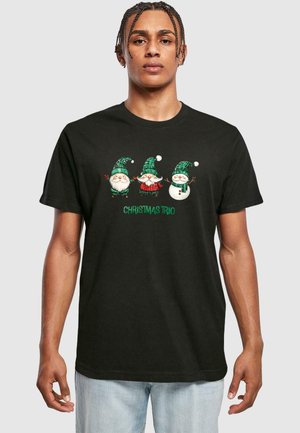 Sort t-shirt med korte ærmer, der har et festligt grafisk motiv af tre karakterer: to nisse-lignende figurer og en snemand, med grønne, hvide og røde accenter.
