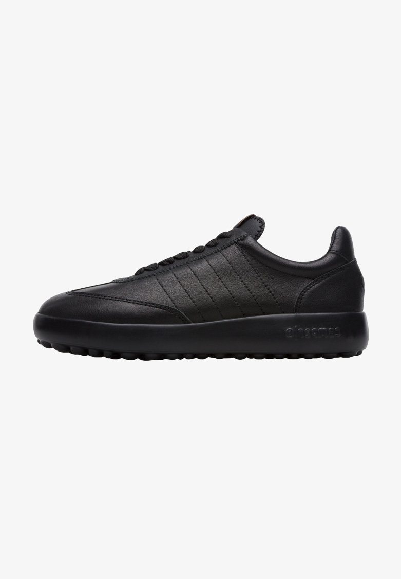 Baskets en cuir noir avec une finition lisse, présentant des lignes de couture horizontales et une semelle en caoutchouc texturé pour une meilleure adhérence.