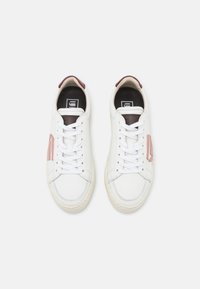 Leather sneakers with a white body, featuring pink and maroon accents, round toe, and white laces. Flat rubber sole.