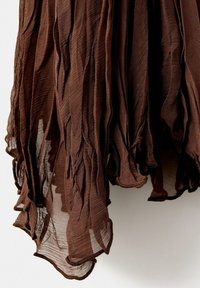 Tissu brun transparent à texture froissée, suspendu librement sur un fond clair, montrant des bords superposés et irréguliers.