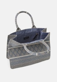 Torebka tekstylna z niebiesko-beżowym wzorem na zewnątrz, dwoma uchwytami oraz podszewką z kieszeniami i przegrodą na zamek.