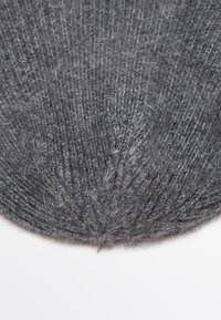 Berretto di lana grigio lavorato a maglia con una consistenza morbida e pelosa e un motivo a coste, dotato di una parte superiore arrotondata e una finitura senza cuciture.