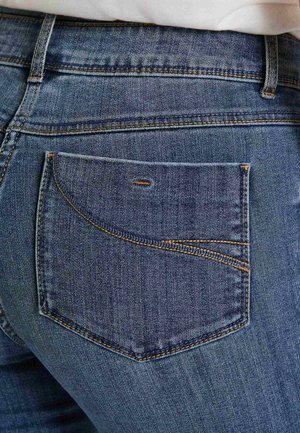 Jean en denim bleu foncé avec une poche arrière dotée d'un détail de couture courbe. La texture est lisse avec des accents de couture visibles.