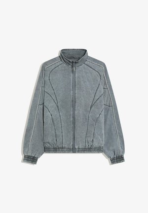 Szürke cipzáras dzseki magas gallérral, rugalmas mandzsettákkal és szegéllyel, ívelt varrási részletekkel és vékony fehér díszítéssel az ujjakon és a vállakon.