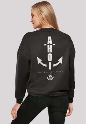 Schwarze Sweatshirt mit einem großen weißen Grafik auf dem Rücken, auf dem der Text "AHOI", Pfeile und ein Ankerdesign zu sehen sind. Rippbündchen an den Ärmeln und am Saum.