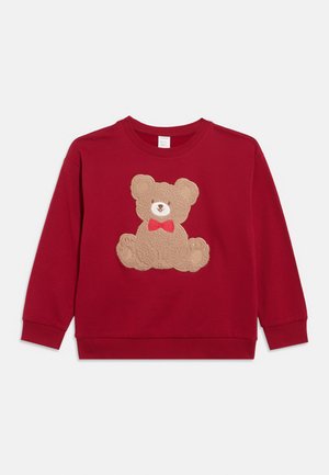 Sweat-shirt rouge à manches longues pour tout-petit, orné d’un appliqué en peluche texturée représentant un ourson portant un nœud papillon rouge, centré sur le devant.