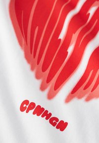 Diseño abstracto rojo en forma de llama sobre letras en bloque rojas en tela blanca, el texto dice "CPNHGN" en una fuente estilizada.