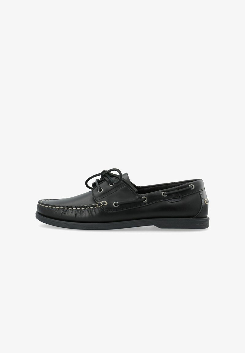 Chaussure bateau en cuir noir avec coutures moc-toe, devant à lacets, œillets latéraux, et semelle basse en caoutchouc sur fond blanc.