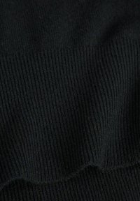 Svart ribbad trikåtyg med en mjuk yta och vertikala linjer. Materialet är lätt och flexibelt med en slät finish.