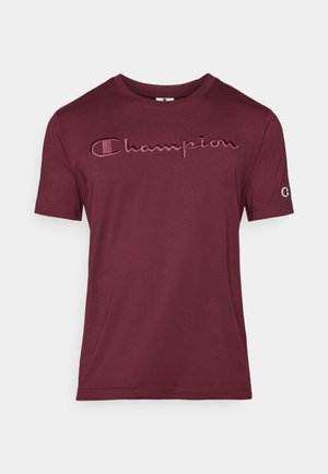 T-shirt à manches courtes bordeaux avec logo "Champion" brodé sur la poitrine et petit patch logo sur la manche gauche.