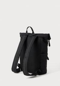 Sac à dos noir avec un design à rabat enroulable, des bretelles rembourrées et ajustables, et un dos en maille texturée pour plus de confort. Comprend une poche latérale et une fermeture éclair.