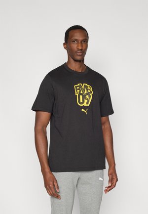 Fekete pamut póló, sárga grafikus szöveggel és Puma logóval az elején. Rövid ujjú, kerek nyakú, laza szabású.