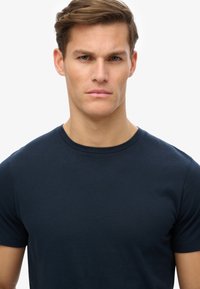 Marineblå, kortærmet t-shirt lavet af bomuld; har en klassisk rund hals og en glat struktur uden mønstre eller logoer.