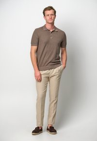 Brun kortärmad polo med krage, ljusbeiga skräddarsydda byxor och bruna slipskor med strukturerad detalj.