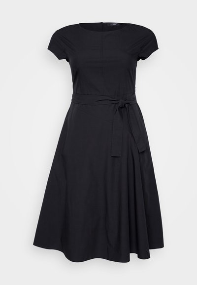 Musta mekko, jossa on lyhyet hihat, pyöreä pääntie, istuva vartalo, vyötäröllä solmittava vyö, laskostettu, valuva helma, sileä kankaan rakenne.