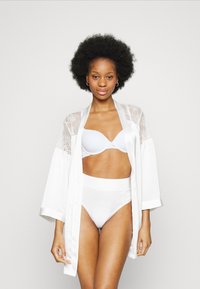 Weißer satinierter Kimono-Robenstil mit Spitzenakzenten, getragen über einem hellblauen BH und hochgeschnittenen Unterhosen, die eine glatte Textur und eine figurbetonte Passform zeigen.