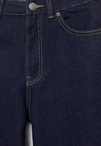 Blugi din denim albastru închis cu cusături portocalii vizibile, închidere cu nasture metalic și buzunar frontal cu detaliu cu nituri.