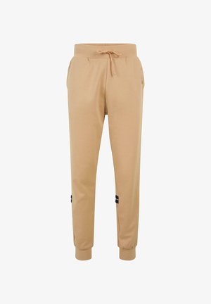 Beige jogger pants made from soft material, featuring an elastic waistband with drawstring and black accent stripes on the sides.