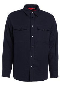 Camicia button-up a maniche lunghe blu navy con due tasche sul petto, fodera interna rossa a contrasto e bottoni neri. Tessuto liscio, vestibilità classica.