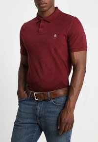 Rode polo-shirt met korte mouwen en een textuurpatroon, voorzien van een drieknopenlijst en een klein geborduurd logo op de linkerkant van de borst.