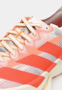 Πορτοκαλί και ροζ αθλητικό παπούτσι με ανώτερο μέρος από δίχτυ, έντονες ρίγες αντίθεσης, υφασμένα κορδόνια και επενδεδυμένη σόλα.