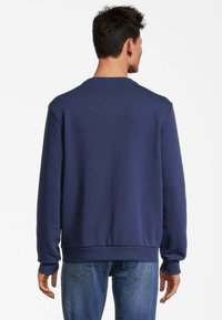 Felpa blu navy con maniche lunghe, scollatura rotonda e polsini a coste. Realizzata in tessuto morbido, presenta una vestibilità comoda e un design minimale.