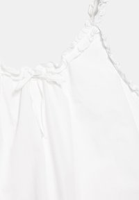 Vêtement blanc sans manches avec un col froncé et un détail de nœud noué au centre devant.