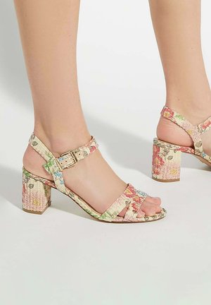 Floral-patterned block heel sandals with adjustable ankle strap, featuring light pastel colors and textured material. Accented with gold hardware.