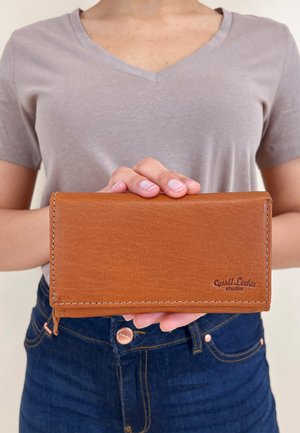 Braune Lederbörse mit glatter Textur, zweifachem Design und kontrastierenden Nähten, mit dem eingeprägten Logo "Gusti Leder studio".