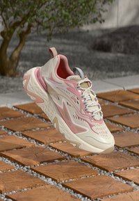 Leichter Sneaker mit cremefarbenem Obermaterial, rosa Akzenten und strukturierten Mustern. Die Sohle ist klobig mit wellenförmigem Design und Gummielementen.