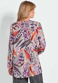 Lange mouwen blouse van lichte stof met een kleurrijk bladenpatroon in paars, oranje en zwart, met een ronde halslijn en zijsplitten.